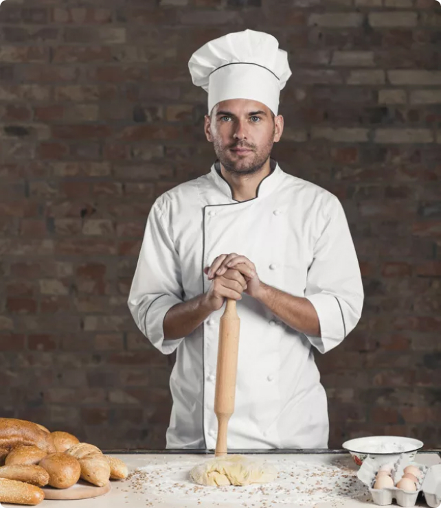 cook is staying behind the table with rolling pin in his hands